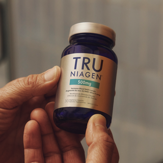 Hand holding a bottle of TRU NIAGEN 500mg supplement